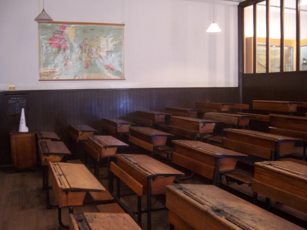 Rows of old wooden school desks beneath a wall map in a preserved classroom.